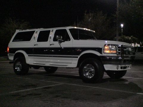 1993 Ford C-350 (Centurion Conversions) - This lifted Ford Bronco Centurion SUV is parked in a lot at night.
