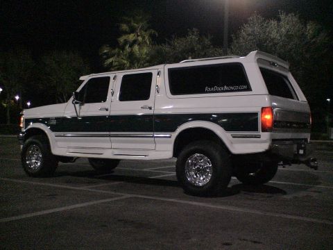 1993 Ford C-350 (Centurion Conversions) - This modified Ford Bronco features a four-door conversion and lifted suspension, seen parked in a lot after dark.