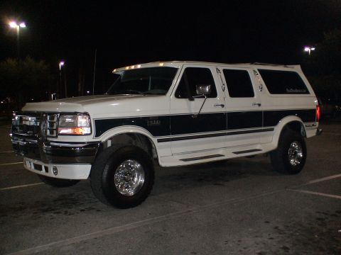 1993 Ford C-350 (Centurion Conversions) - White Ford SUV with dark side trim and chrome wheels parked at night.