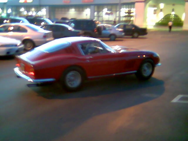 Red coupe in a parking lot, rear quarter view