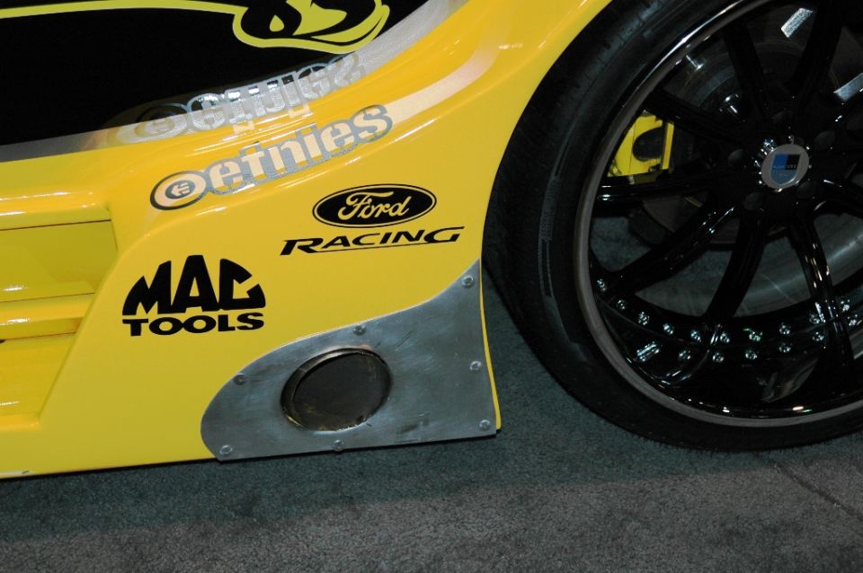 Yellow race car side panel with Ford Racing and MAC Tools logos, and a large exhaust pipe