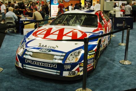 1991 Ford Taurus - A Ford Fusion race car with AAA sponsorship is displayed indoors.