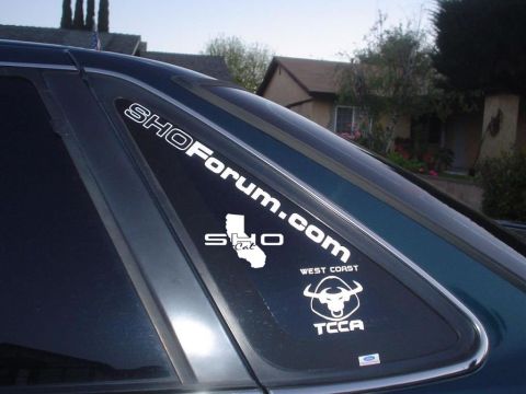 1993 Ford Taurus - A car's rear window displays various club and brand decals, including SHOForum.com and a Ford logo.