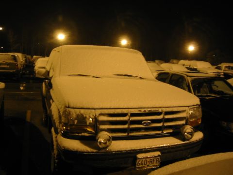 1995 Ford Bronco - A 1995 Ford Bronco sits parked under a light snowfall at night.