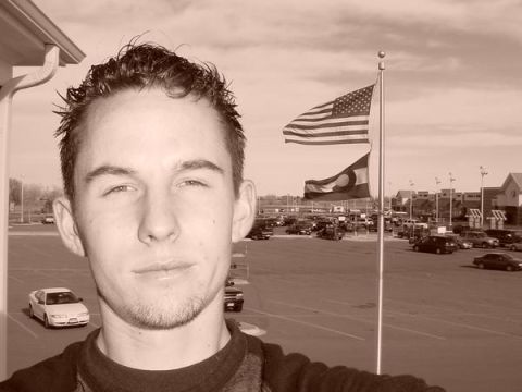 1996 Ford Probe - A man poses for a selfie in a parking lot with flags and other vehicles visible.