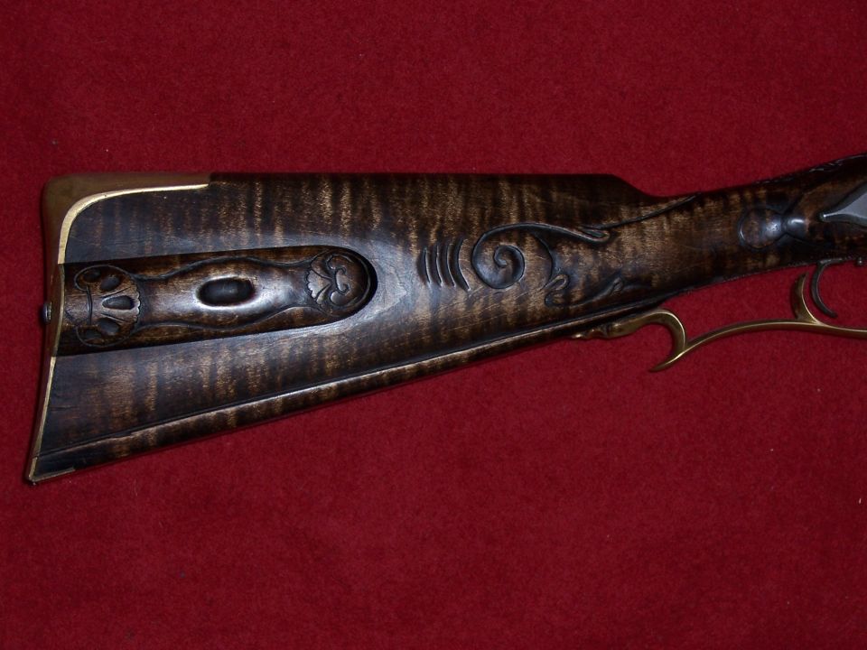 Close-up of ornate wooden rifle stock with brass accents