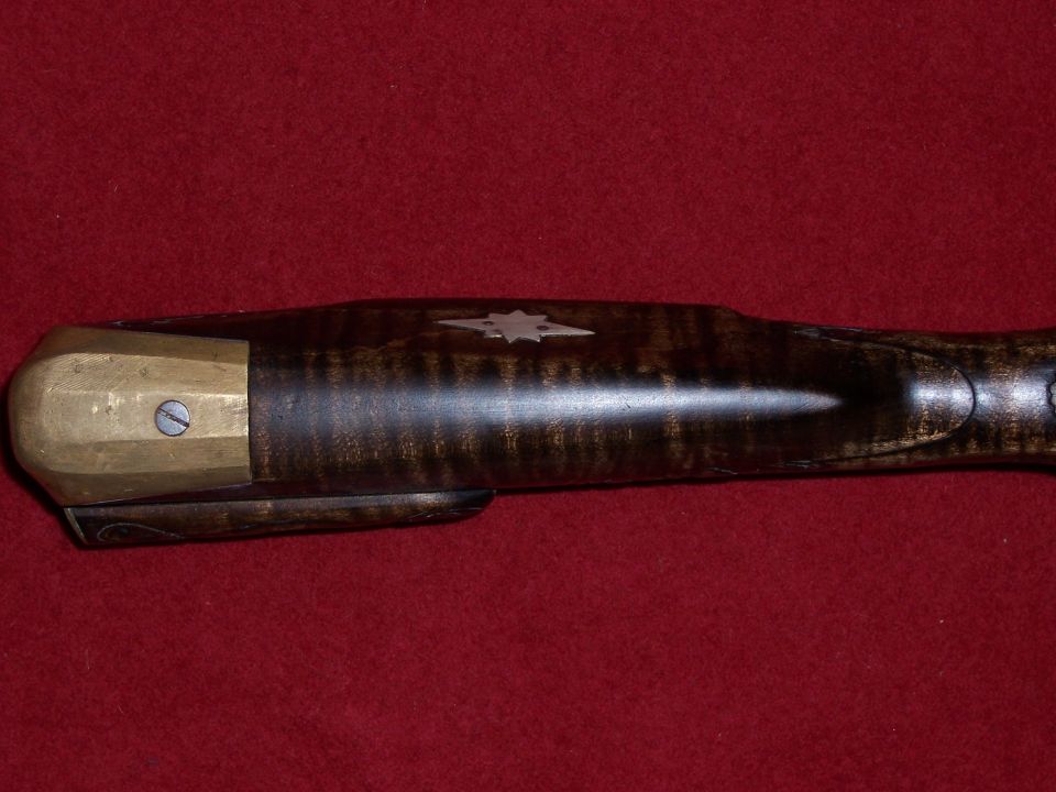 Close-up of antique firearm stock with brass buttplate and star inlay