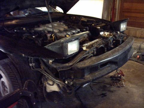 1995 Ford Probe - Front view of a 1995 Ford Probe with its hood open, revealing the engine and pop-up headlights.
