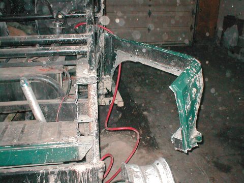 1983 Ford Bronco - Detail of a green fender flare and vehicle chassis, with visible damage and exposed metal components.
