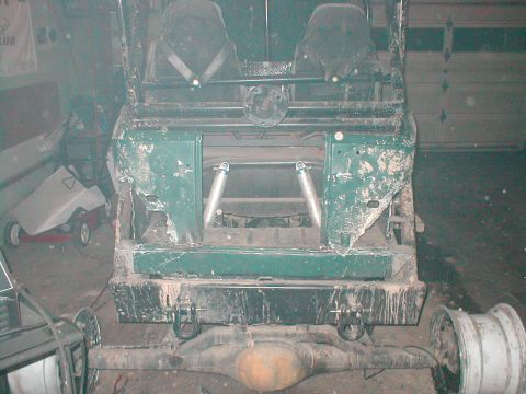 1983 Ford Bronco - The rear suspension and frame of a vehicle are visible, with two seats in the foreground.