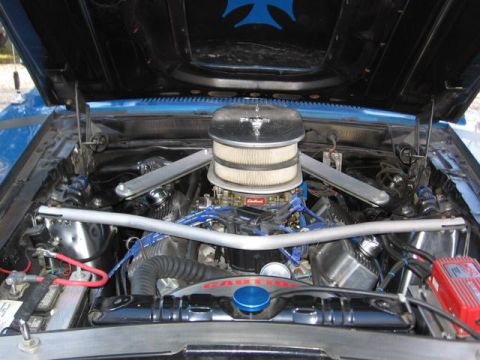 1983 Ford Bronco - The engine bay of a blue car is shown with various aftermarket parts and modifications.