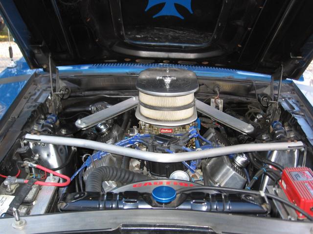 Blue car engine bay with chrome accents, dual air filters, and a red ignition box