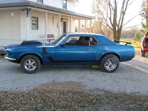1983 Ford Bronco - A blue 1970 Ford Mustang Boss 302 is parked in a gravel driveway in front of a white house.