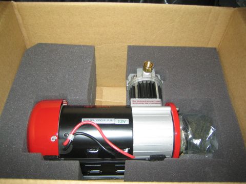 1990 Ford Bronco - 12-volt winch with a red motor housing, aluminum drum and red wiring sits packed in gray foam inside a cardboard shipping box.