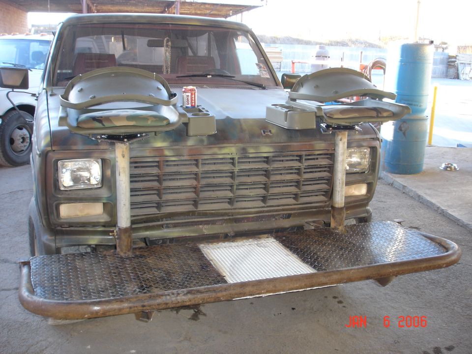 Front view of a camouflaged truck with two mounted seats on the hood and a diamond plate bumper