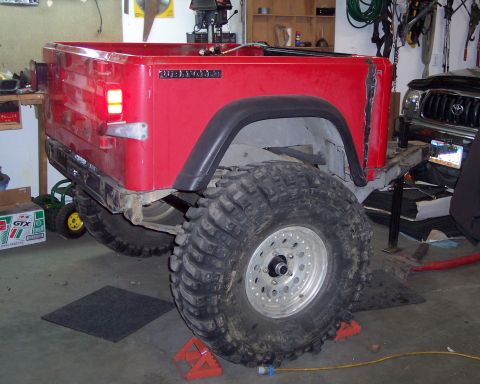 2003 Jeep TJ - Rear view of a red Jeep Wrangler, identified by the "WRANGLER" badge, with oversized tires.