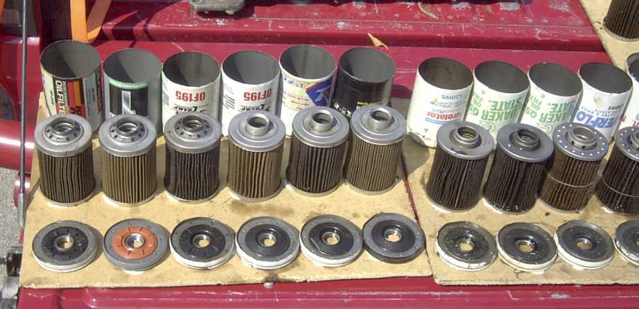 Several oil filters and their bases laid out on a red surface. Some filters are in their original cans
