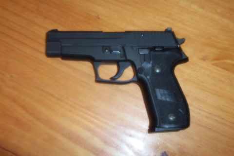 1998 Ford Crown Victoria - A black handgun rests on a wooden table, showing its trigger and grip.