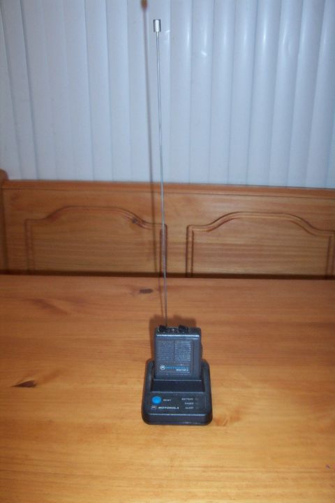 1998 Ford Crown Victoria - A Motorola radio sits on its charging base, with a tall antenna extended upwards.