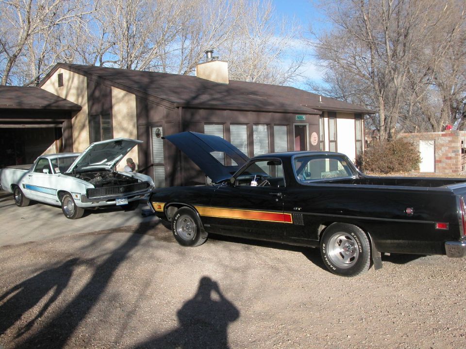1972 Ford Ranchero and a white Ranchero parked outside a house