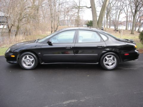1998 Ford Taurus - Side profile of a black 1998 Ford Taurus sedan parked on an asphalt surface.