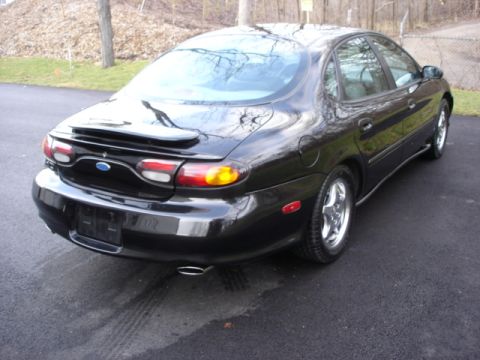 1998 Ford Taurus - This black Ford sedan has a spoiler and distinctive taillights, suggesting a model year earlier than claimed.