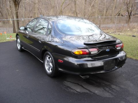 1998 Ford Taurus - Rear view of a black 1998 Ford Taurus sedan with a spoiler and chrome wheels.