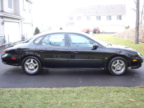 1998 Ford Taurus - Side profile of a black 1998 Ford Taurus sedan parked on a driveway.