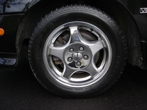 1998 Ford Taurus - Close-up of a chrome wheel and tire on a black vehicle.