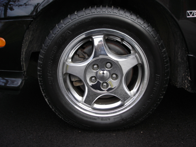 Close-up of a chrome five-spoke wheel with a black tire on a black car