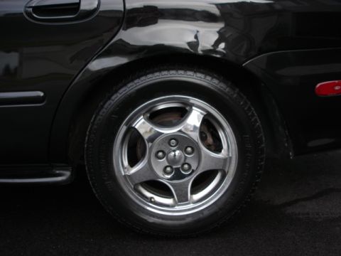 1998 Ford Taurus - The rear wheel and fender of a black sedan are shown in this close-up shot.