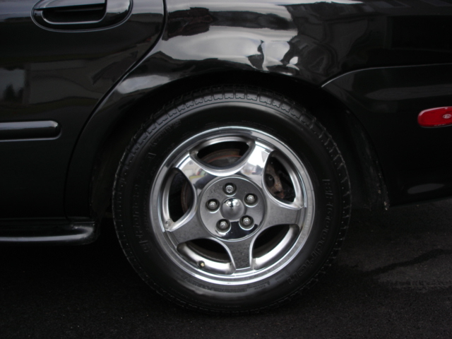Close-up of a black sedan's rear wheel and fender