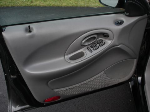 1998 Ford Taurus - Close-up of a car's interior door panel with window controls and a red reflector.