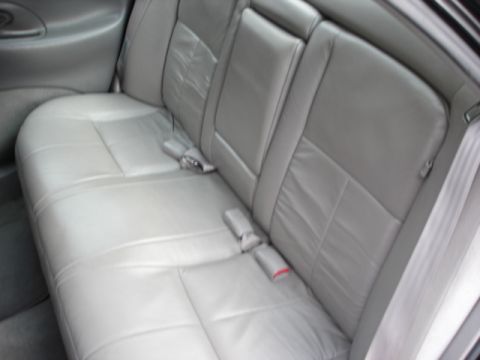 1998 Ford Taurus - The interior of a car shows the back seat with gray leather upholstery and seatbelts.