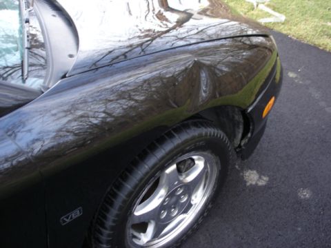 1998 Ford Taurus - The V8 badge is visible on the front fender of this black 1998 Ford Taurus, which has a noticeable dent.