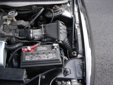 1998 Ford Taurus - The engine bay shows a car battery and various hoses and components.