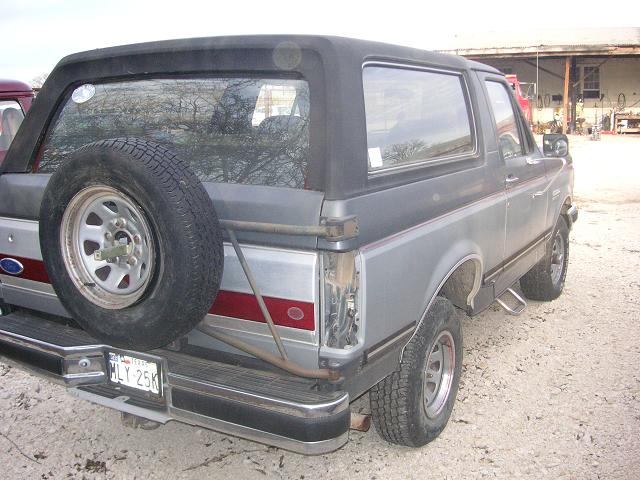 Gray SUV's rear with spare tire, red stripe, and Texas license plate MLY 25K
