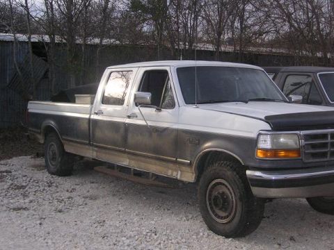 1990 Ford Bronco - This Ford F-350 pickup truck is parked next to another vehicle.