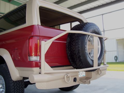 1989 Ford Bronco - Rear view of a red and tan 1989 Ford Bronco, a spare tire mounted on a custom bumper.
