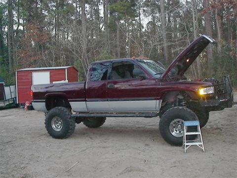 2001 Dodge 1500 - A lifted 2001 Dodge 1500 pickup truck is parked with its hood open, revealing the engine compartment.