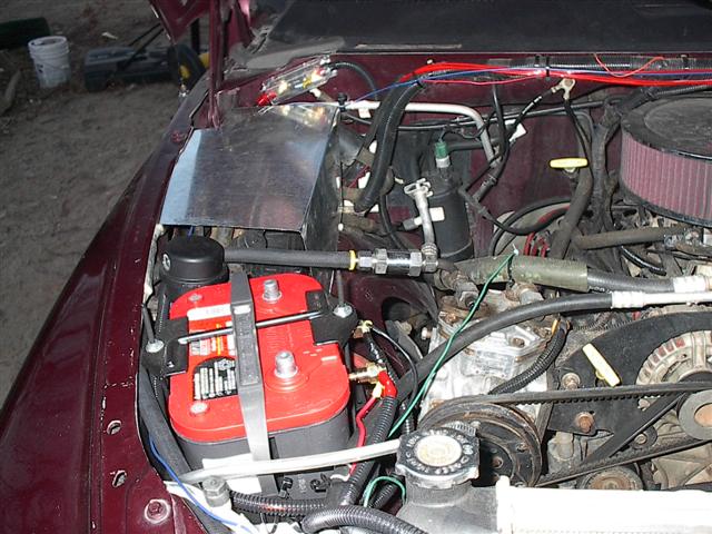 Engine bay showing red Optima battery, air filter, belts, and custom aluminum panel