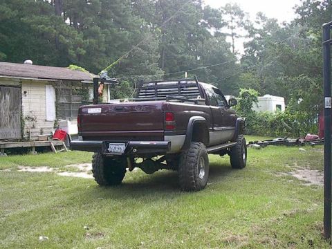 2001 Dodge 1500 - A maroon 2001 Dodge 1500 pickup truck is parked on a grassy area next to a dilapidated house.