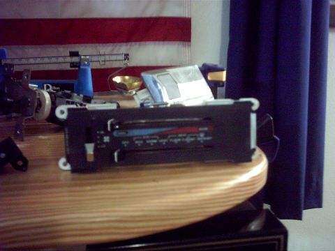 1996 Ford Bronco - A car radio control panel is shown on a wooden table, with an American flag in the background.