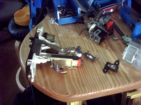 1996 Ford Bronco - Various disassembled steering column components and wiring are laid out on a wooden surface.