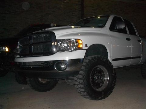 2001 Dodge 1500 - A lifted white Dodge pickup truck is shown from the front-right side, with another vehicle visible to its left.