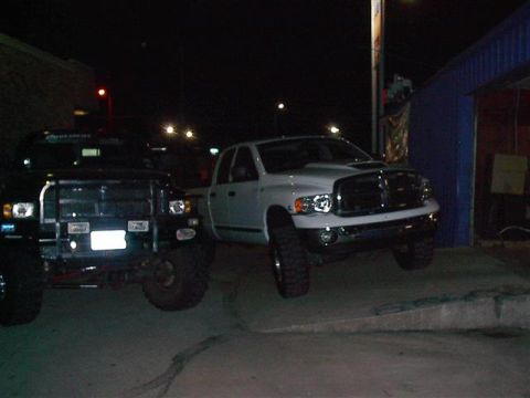 2001 Dodge 1500 - Two Dodge Ram pickup trucks are parked outside a building at night.