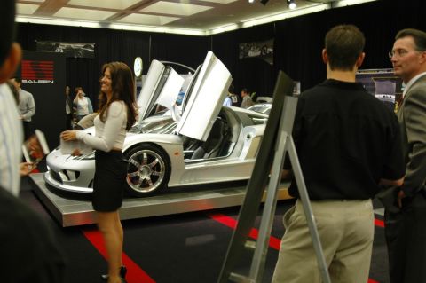 1991 Ford Taurus - A white supercar with its distinctive butterfly doors open is showcased at an auto show, drawing attention from onlookers.