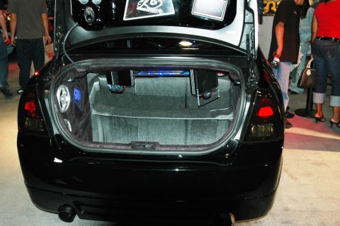 1991 Ford Taurus - The trunk of a black car is open, revealing a custom audio system with speakers and blue LED lighting.
