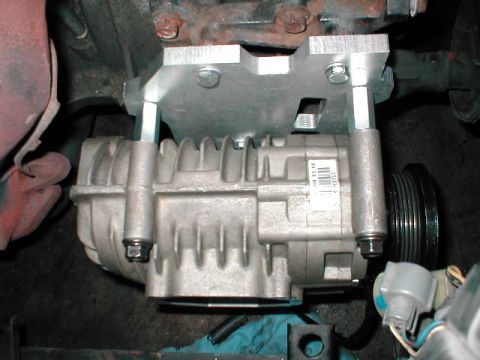 1992 Ford Probe - Close-up of a supercharger unit installed on an engine, showing mounting hardware and a label.