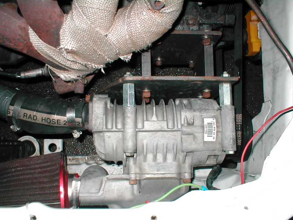 Close-up of engine part with hoses and belts, some wrapped in insulation
